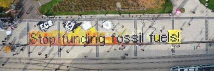 Aerial photo of an artwork on train tracks that says "Stop funding fossil fuels"