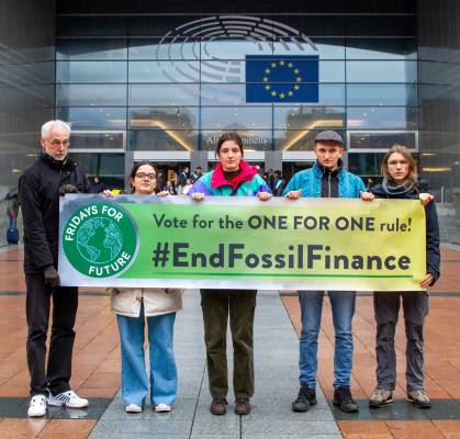 Aktivist*innen stehen vor dem EU Parlament mit einem Banner, auf dem #EndFossilFinance steht.