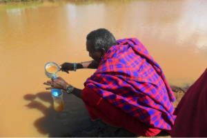 Pastor coletando água para beber em uma fonte contaminada, no norte da Tanzânia. Ele está entre os 650 milhões de pessoas sem acesso à água limpa e segura.