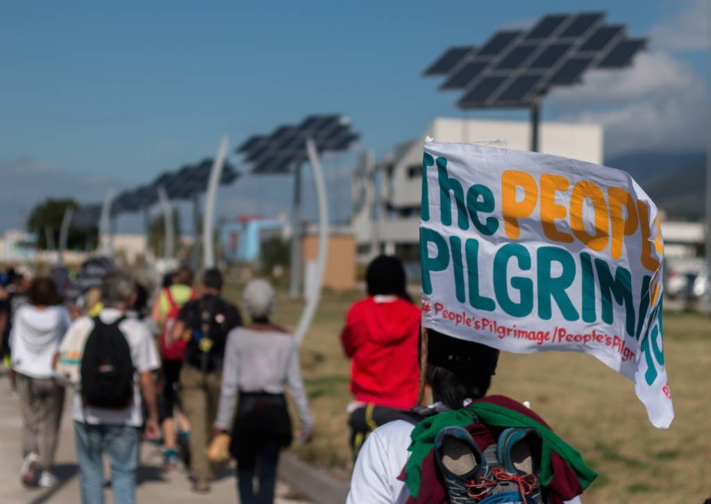 Yeb Saño, the Pilgrims and the Pacific Climate Warriors, walk by solar energy panels.