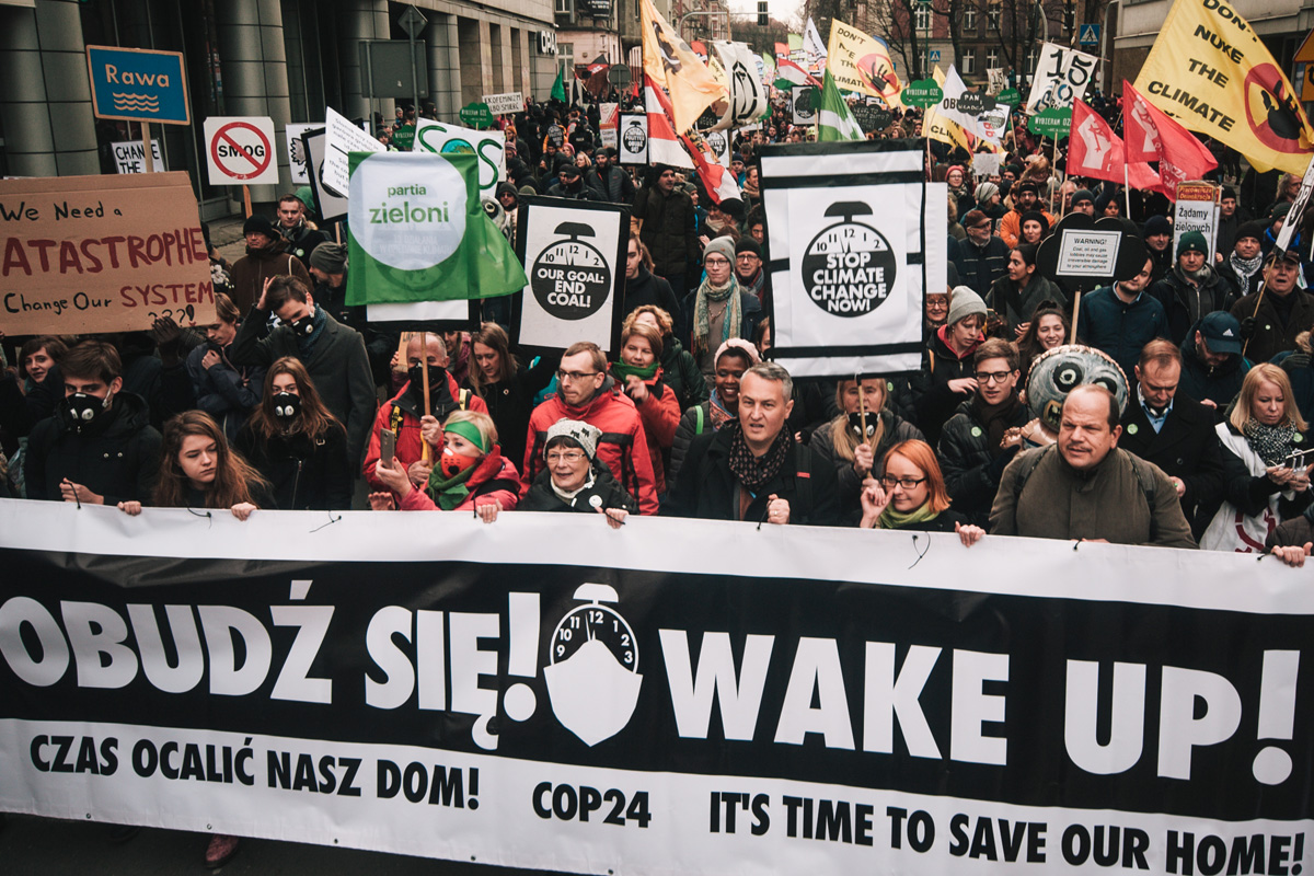 People marching with banner that says obudź się in Polish and translates to Wake up in english.