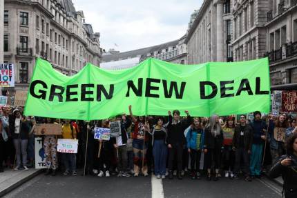 people marching and carrying Green New Deal banner