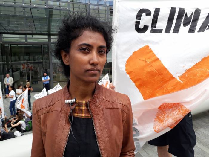 Young activist looking into camera with background of fossil free flags