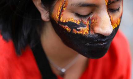 Close up of a young woman with her face painted with fire and the silhouette of a kangaroo.