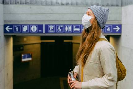 A woman wearing a facemask at the entrance to metro station