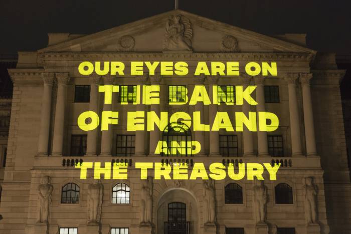 Yellow text reading "Our eyes are on the Bank of England and the Treasury' being projected onto the Bank of England at night-time