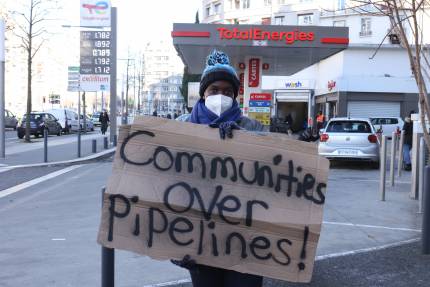 Anti EACOP protester holding sign saying 'Comunities over pipelines'